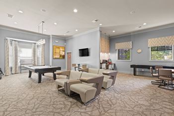 Clubhouse with a TV seating area, pool table, shuffle board, and business center.